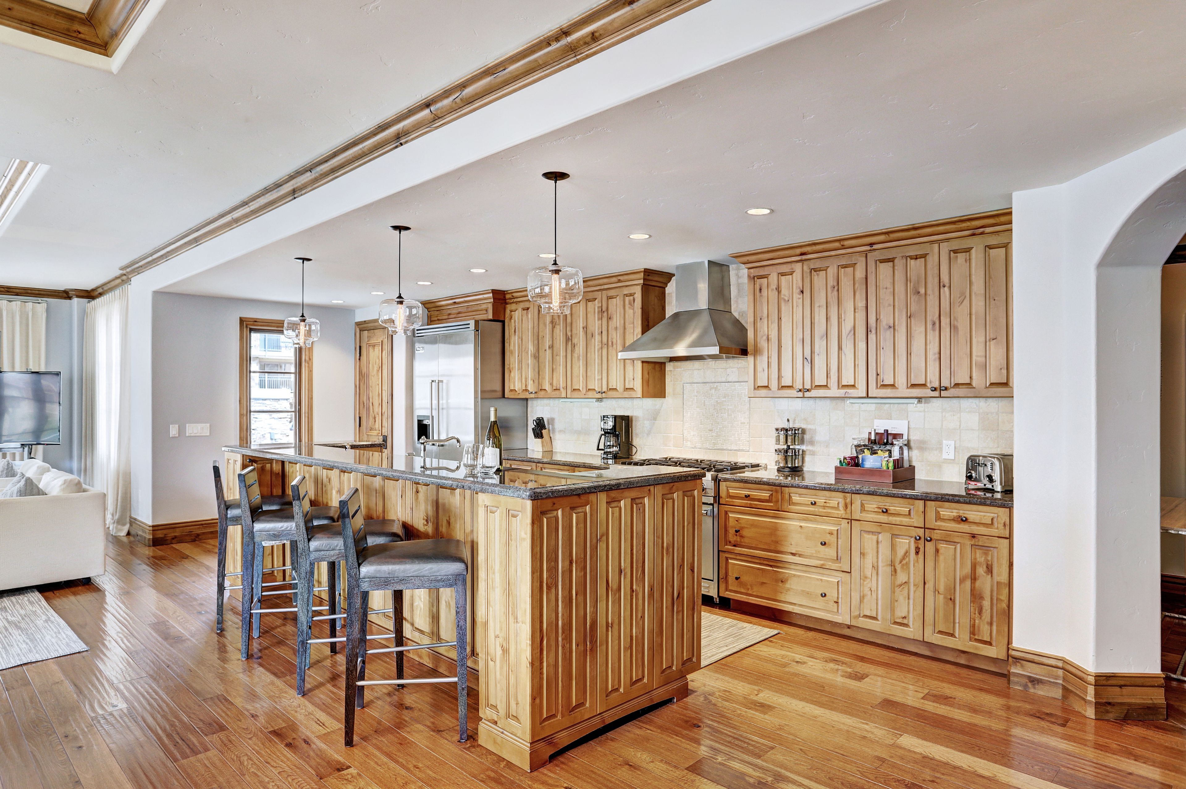 A spacious kitchen with wooden cabinetry, a central island with bar stools, and a large window providing natural light.