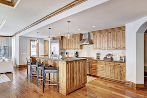 A spacious kitchen with wooden cabinetry, a central island with bar stools, and a large window providing natural light.