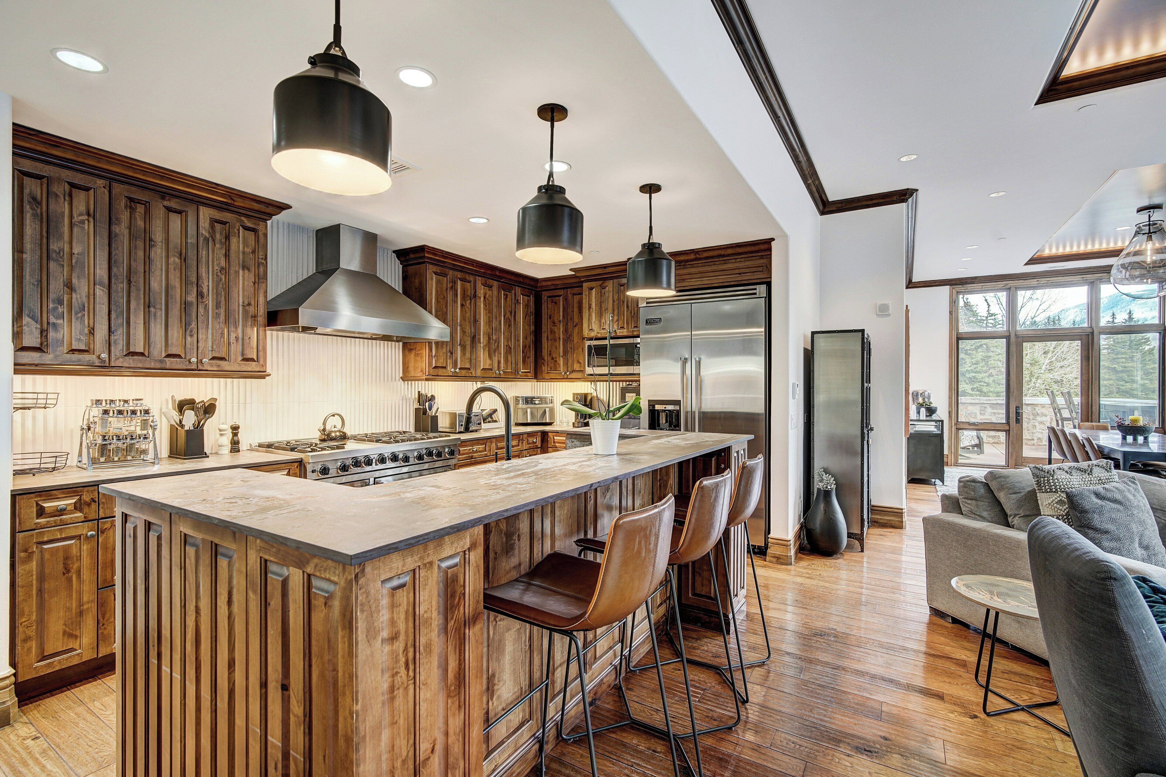 A modern kitchen with wooden cabinets, stainless steel appliances, and a large island with bar stools.