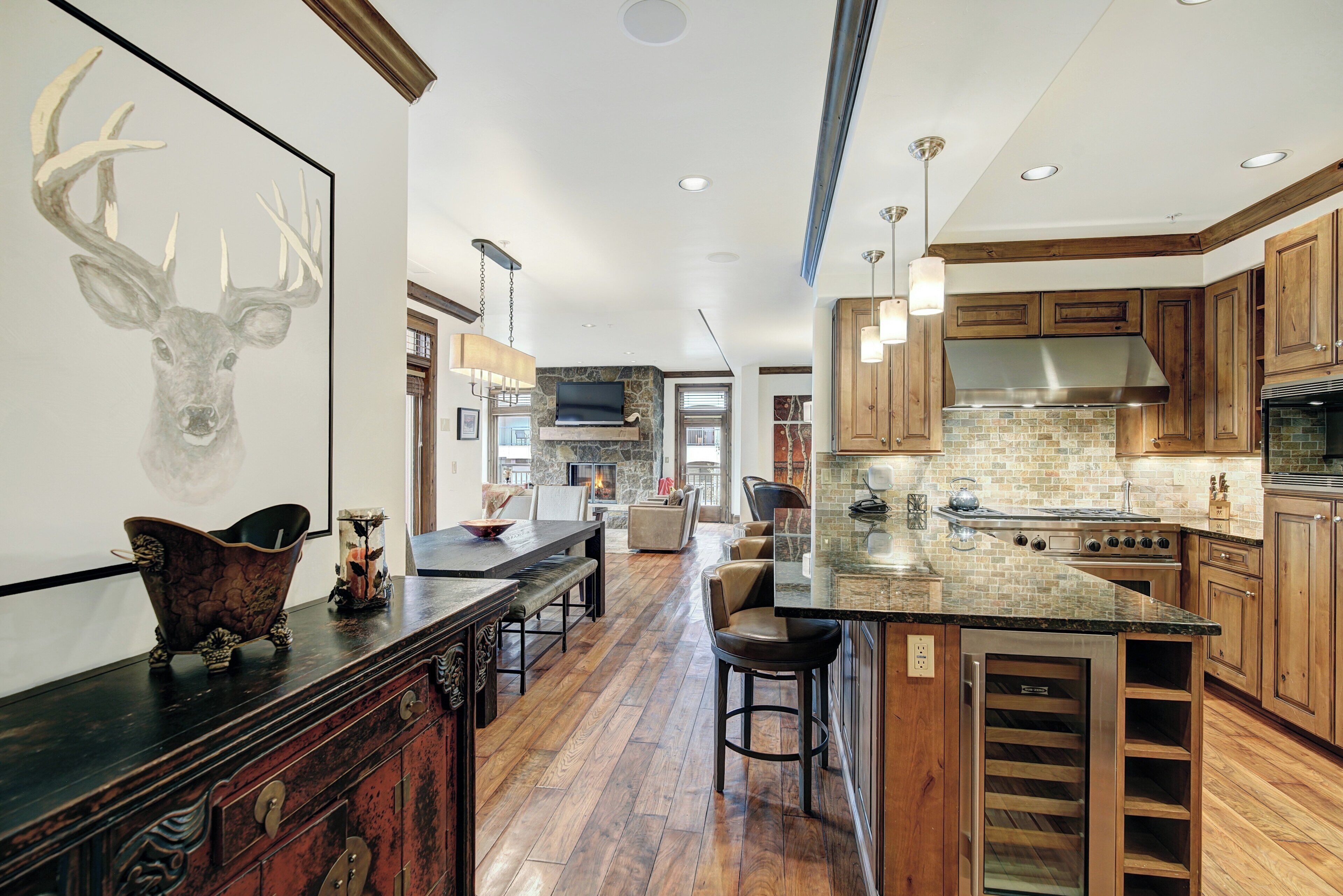 A spacious kitchen with a large island, wooden cabinets, and a stone backsplash.