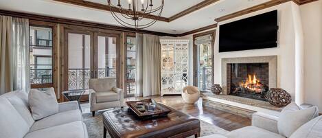 Un salón amplio con chimenea, asientos cómodos y un televisor grande.