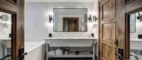 A modern bathroom with a large mirror, two sinks, and a wooden vanity.
