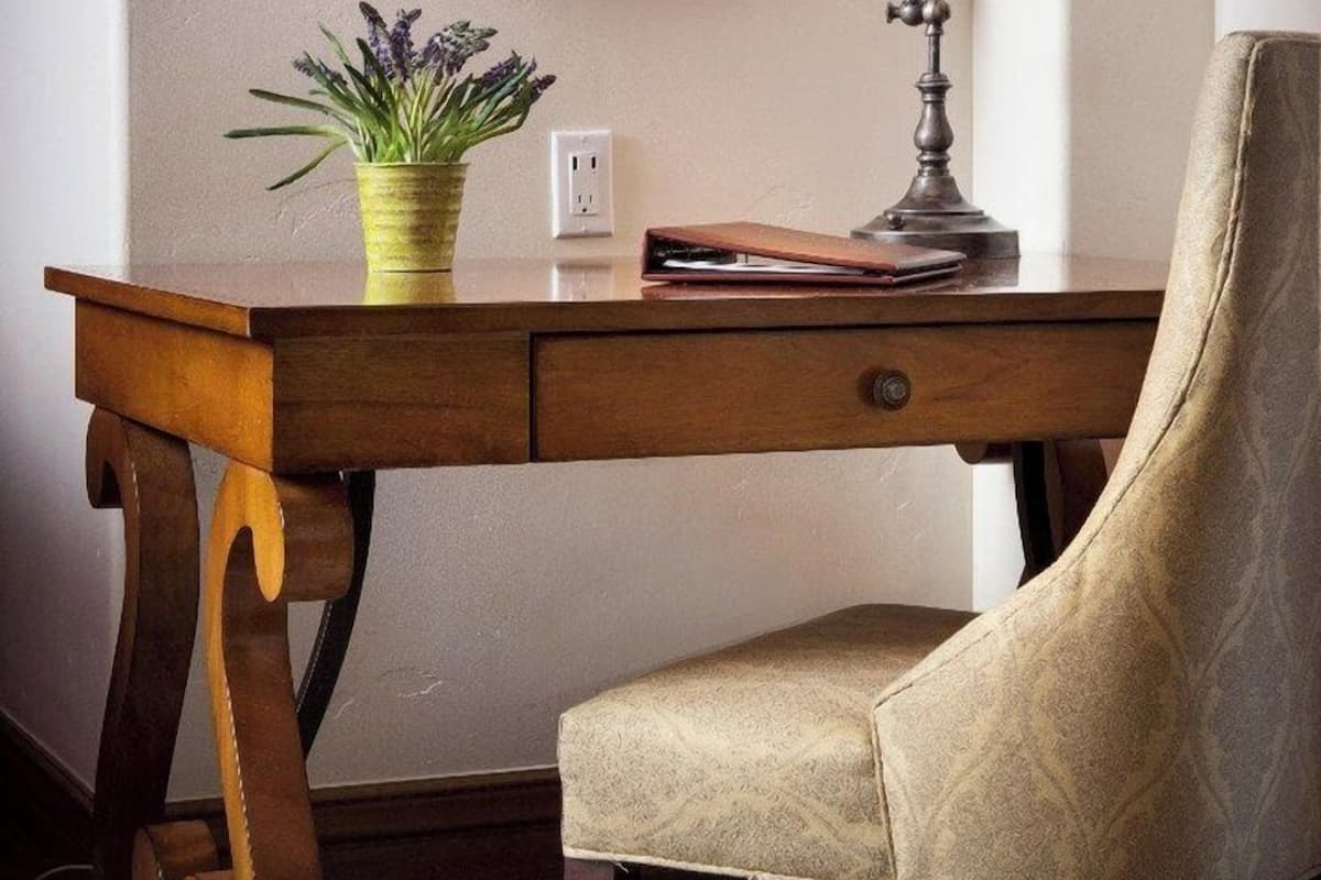 A wooden desk with a lamp, a chair, and a potted plant.
