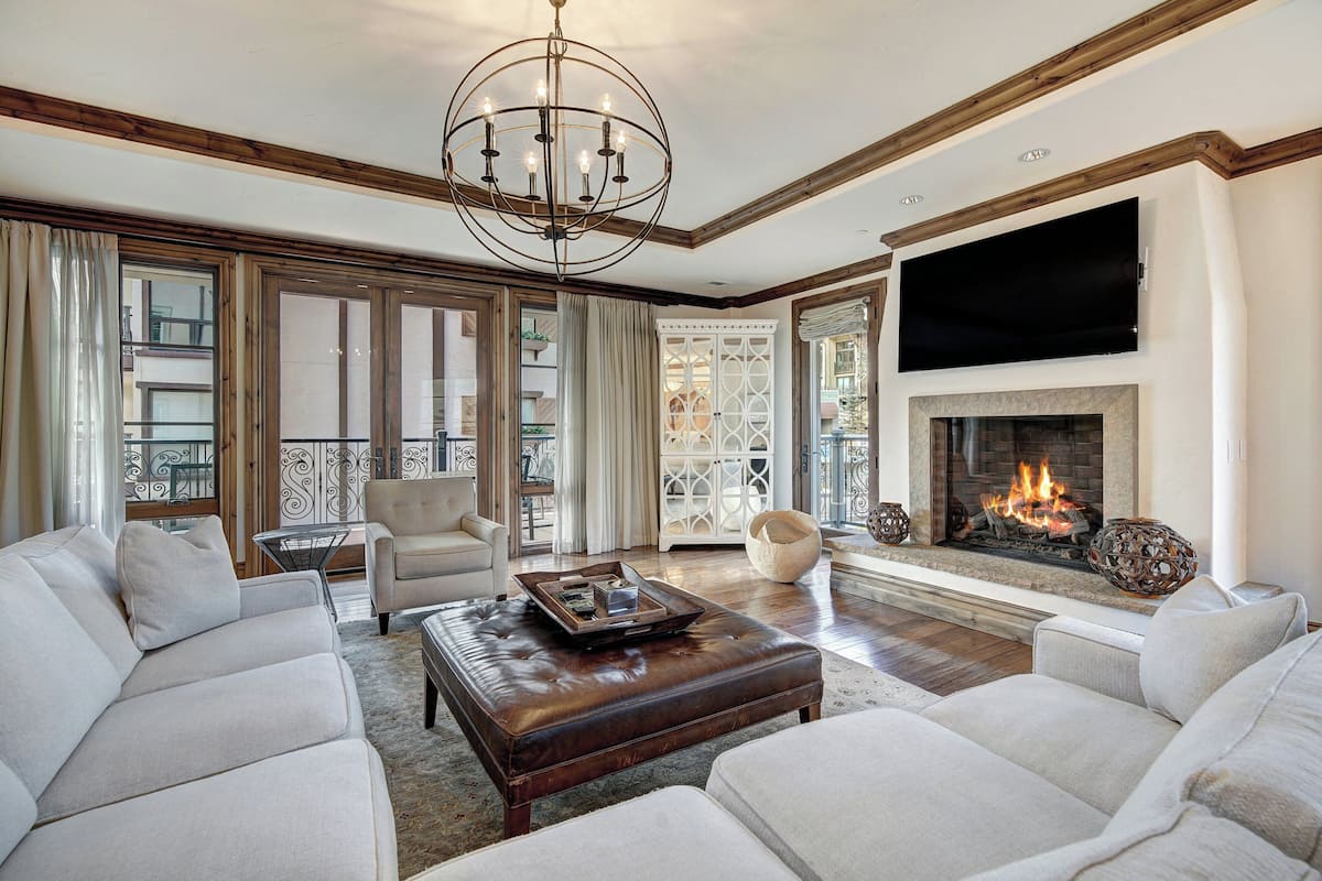 A spacious living room with a fireplace, comfortable seating, and a large TV mounted on the wall.