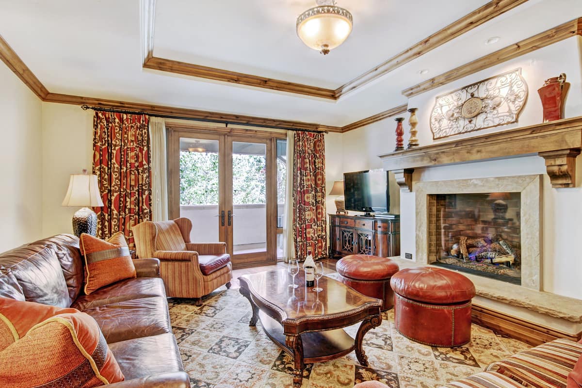 A living room with a leather sofa, a wooden coffee table, a fireplace, and a television.