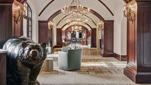 A spacious lobby with a high ceiling, a chandelier, and a bear sculpture. - The Arrabelle, A RockResort, by Vail Resorts (Vail)