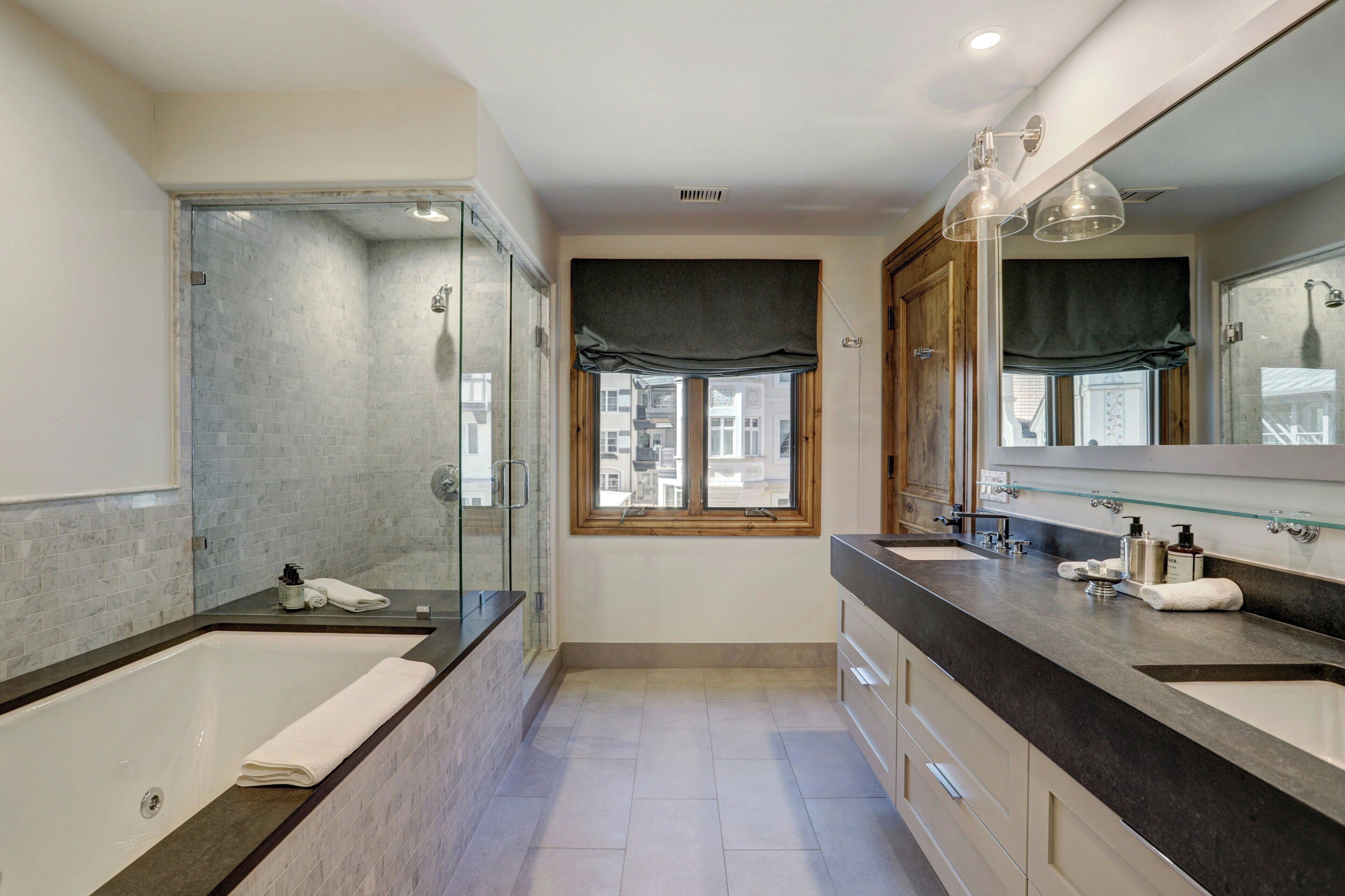 Une salle de bain moderne dotée d’une grande baignoire, d’une douche à parois de verre et d’un meuble-lavabo avec un grand miroir.