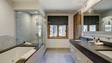 A modern bathroom with a large bathtub, a glass-enclosed shower, and a vanity with a large mirror.