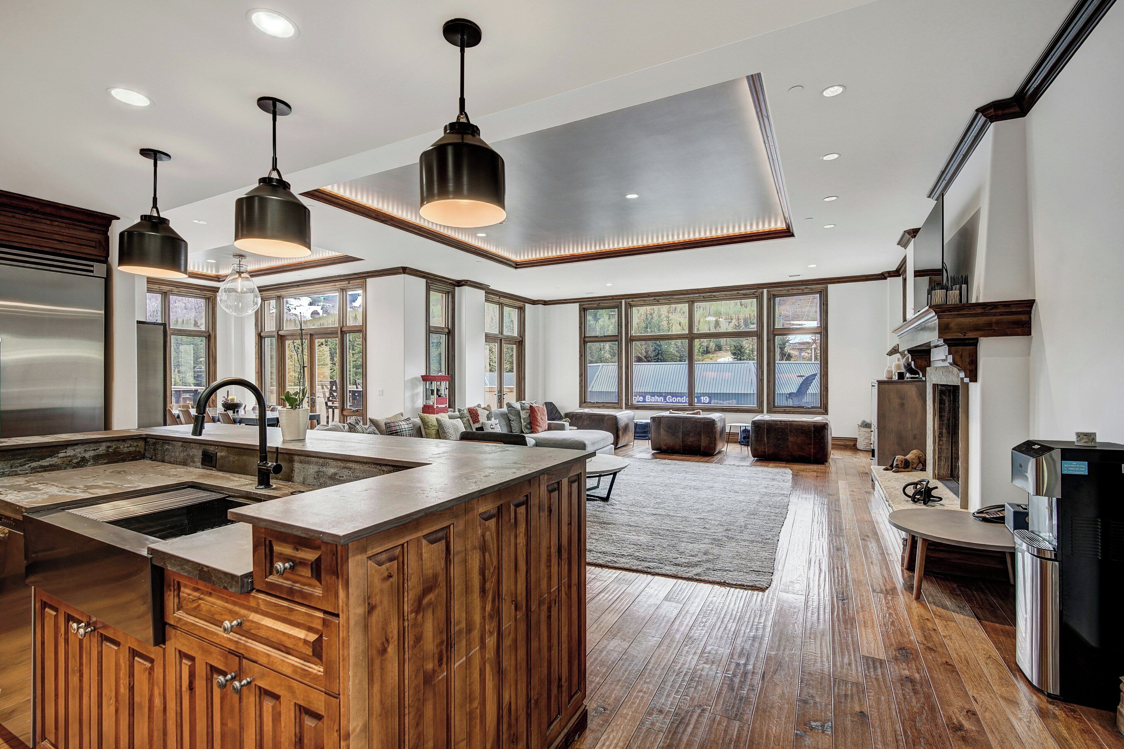 A spacious kitchen with a large island, wooden cabinets, and modern pendant lighting.