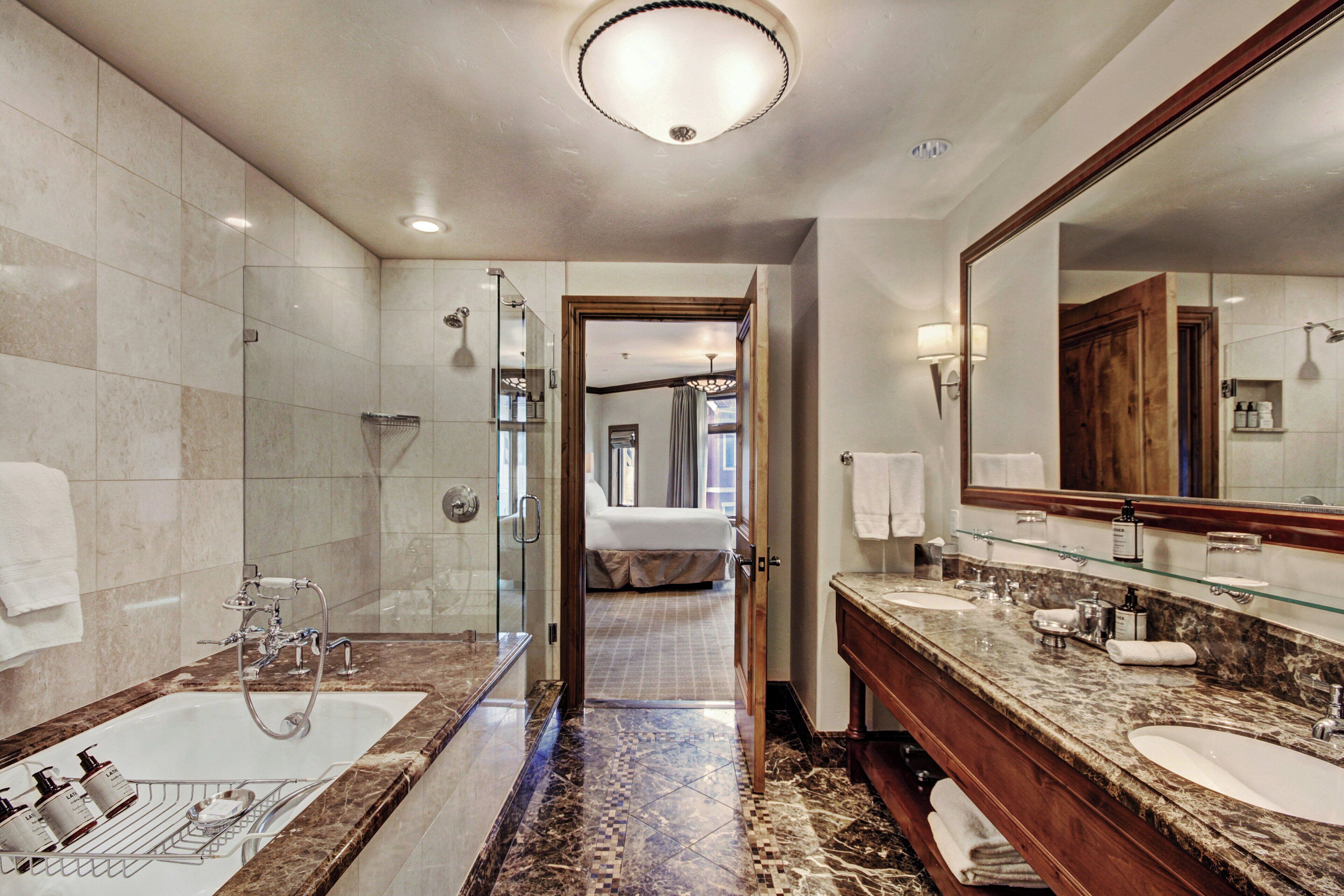 A modern bathroom with a glass-enclosed shower, a large vanity with two sinks, and a walk-in shower.