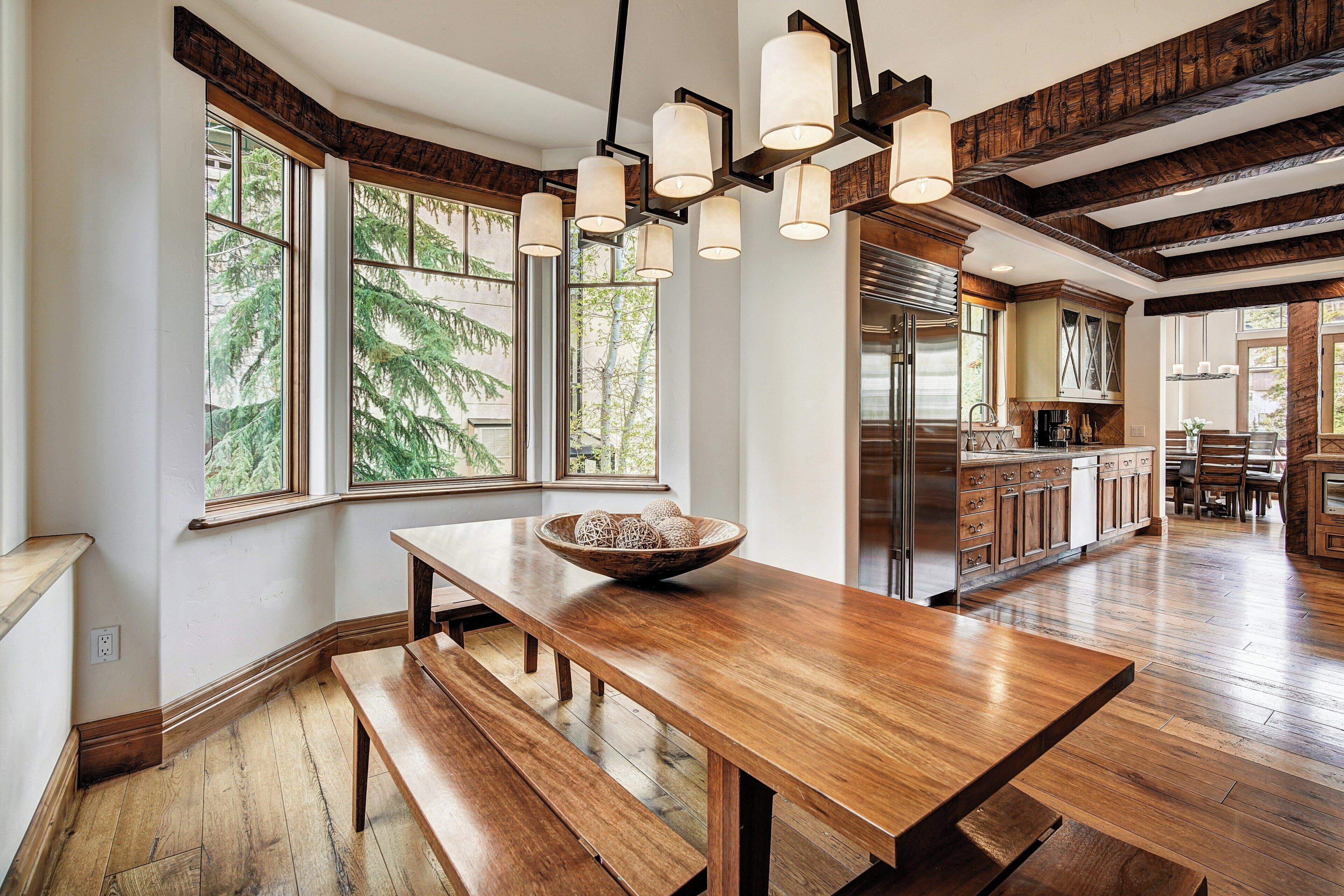 A spacious kitchen with wooden flooring, a large wooden table, and a bowl of decorative items.