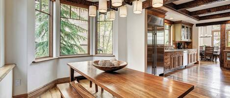 A spacious kitchen with wooden flooring, a large wooden table, and a bowl of decorative items.