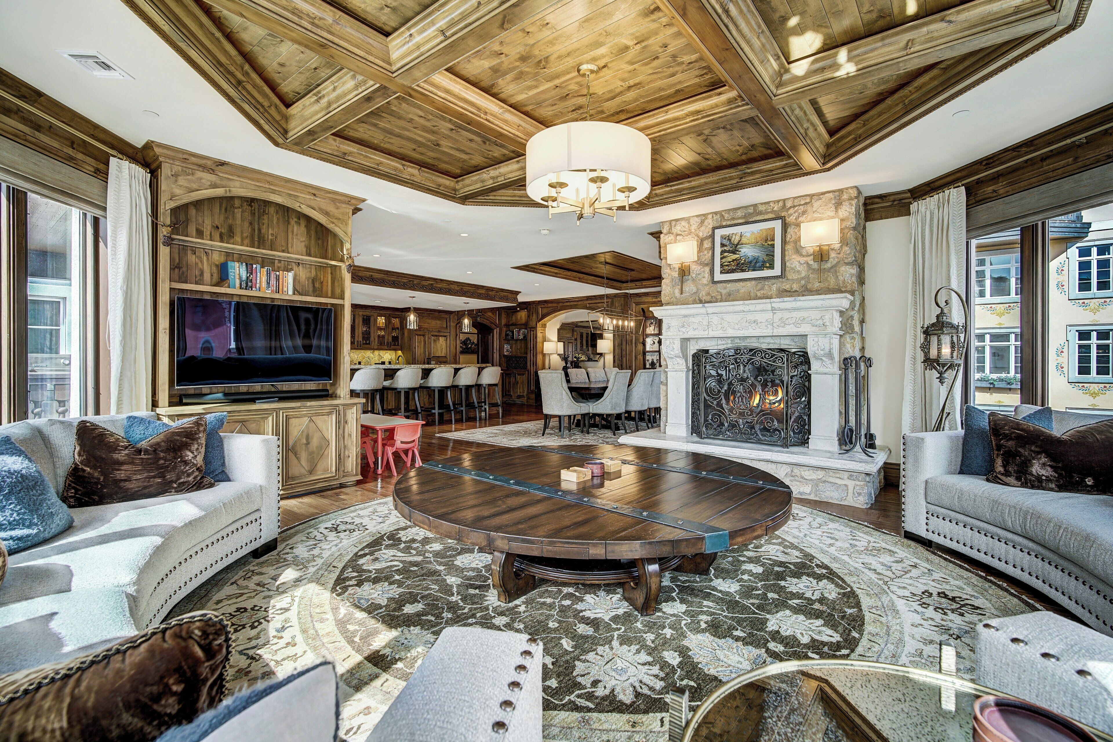A spacious living room with a large round coffee table, comfortable seating, a fireplace, and a television.