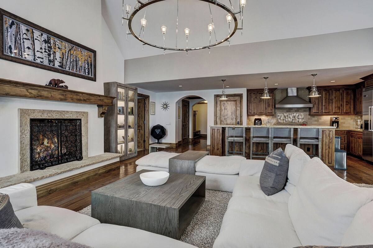 A spacious living room with a fireplace, a dining area, and a kitchen with wooden cabinets and a stainless steel refrigerator.