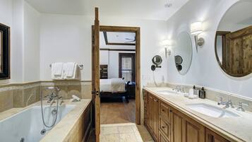 Un baño con bañera, dos lavamanos, armarios de madera y un espejo.