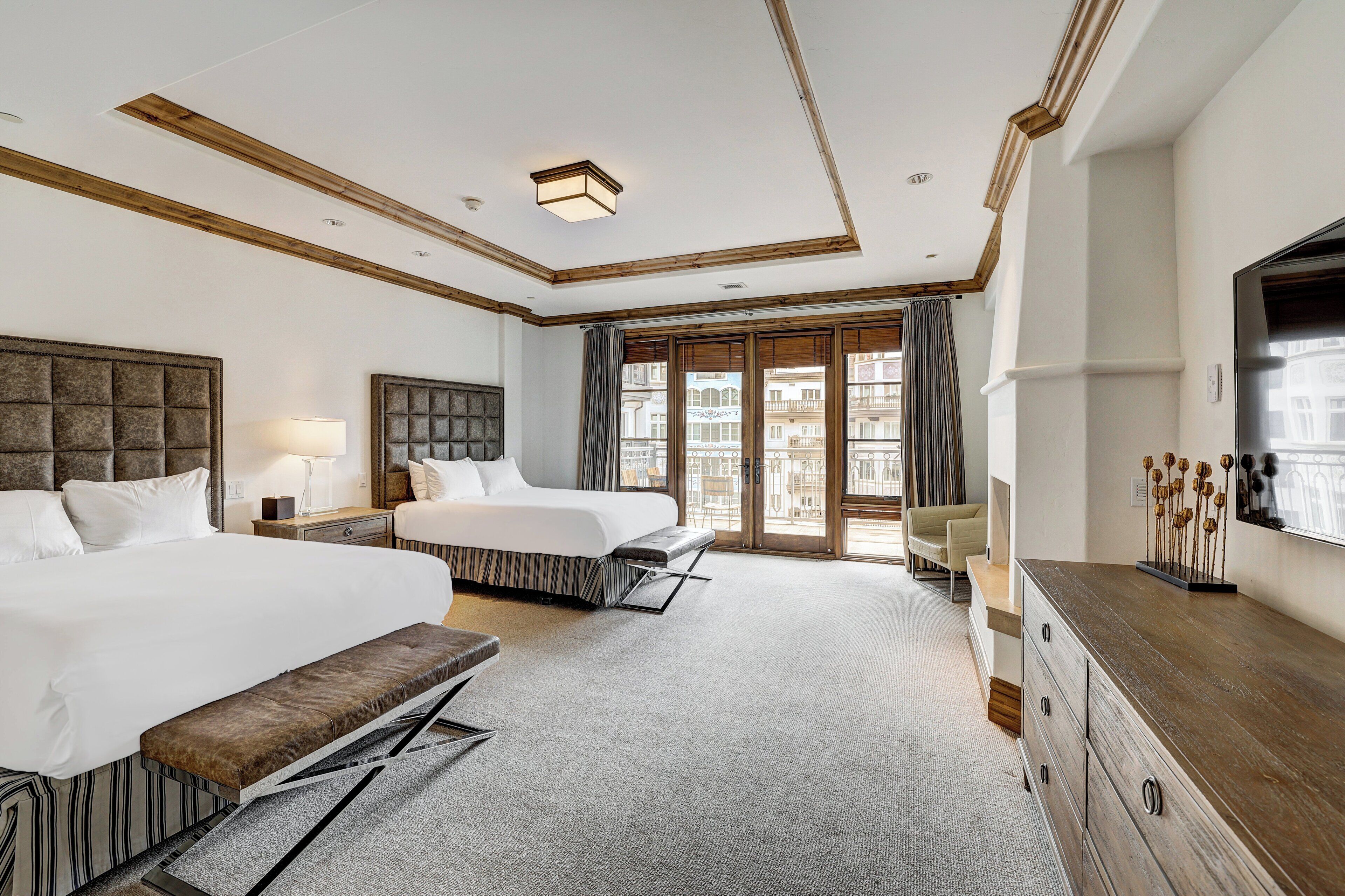 Une chambre d’hôtel avec deux lits, une grande fenêtre, une commode en bois et un téléviseur.