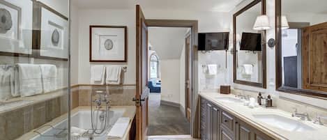 A modern bathroom with a glass-enclosed shower, double sinks, and a large mirror.