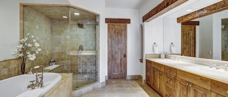 A modern bathroom with a glass-enclosed shower, a large bathtub, wooden cabinets, and a large mirror.