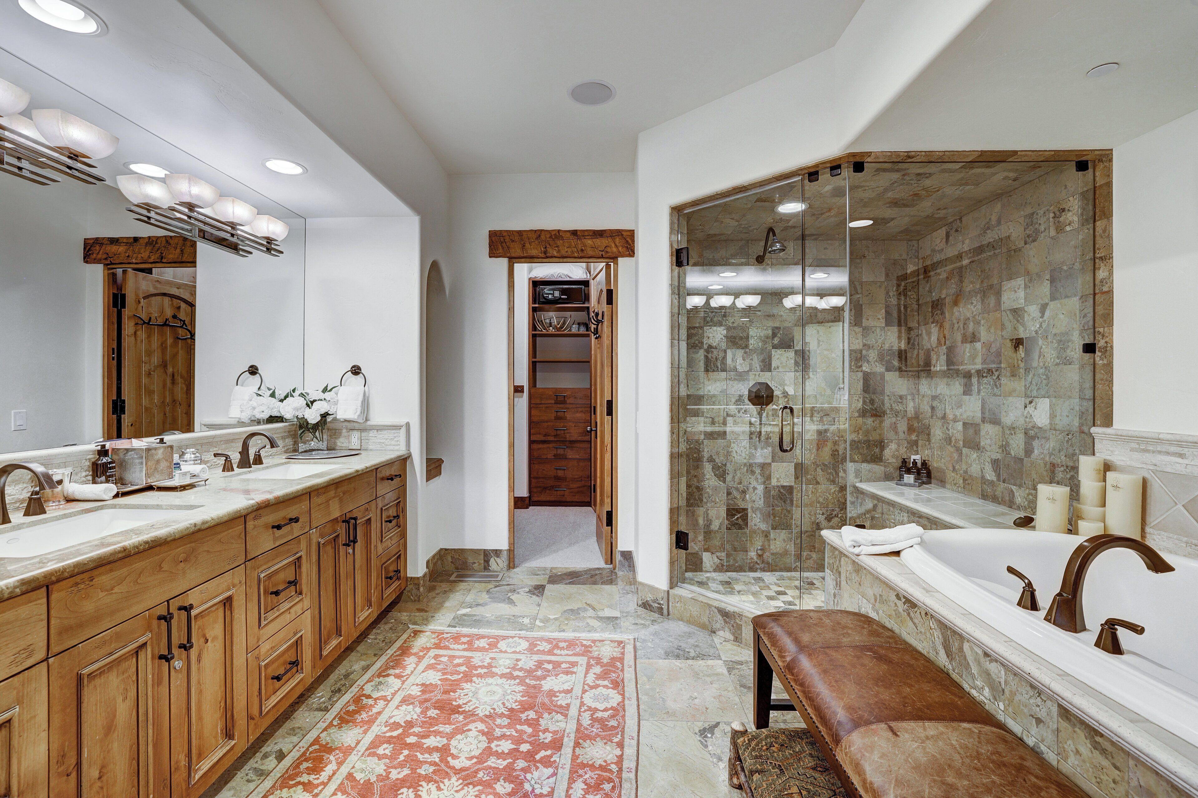 A modern bathroom with a large vanity, a separate shower area, and a bench.