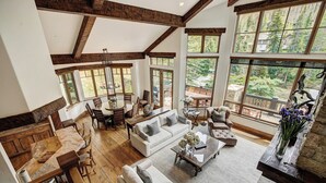 A spacious living area with a high ceiling, wooden beams, large windows, and a view of the outdoors. - The Arrabelle, A RockResort, by Vail Resorts (Vail)