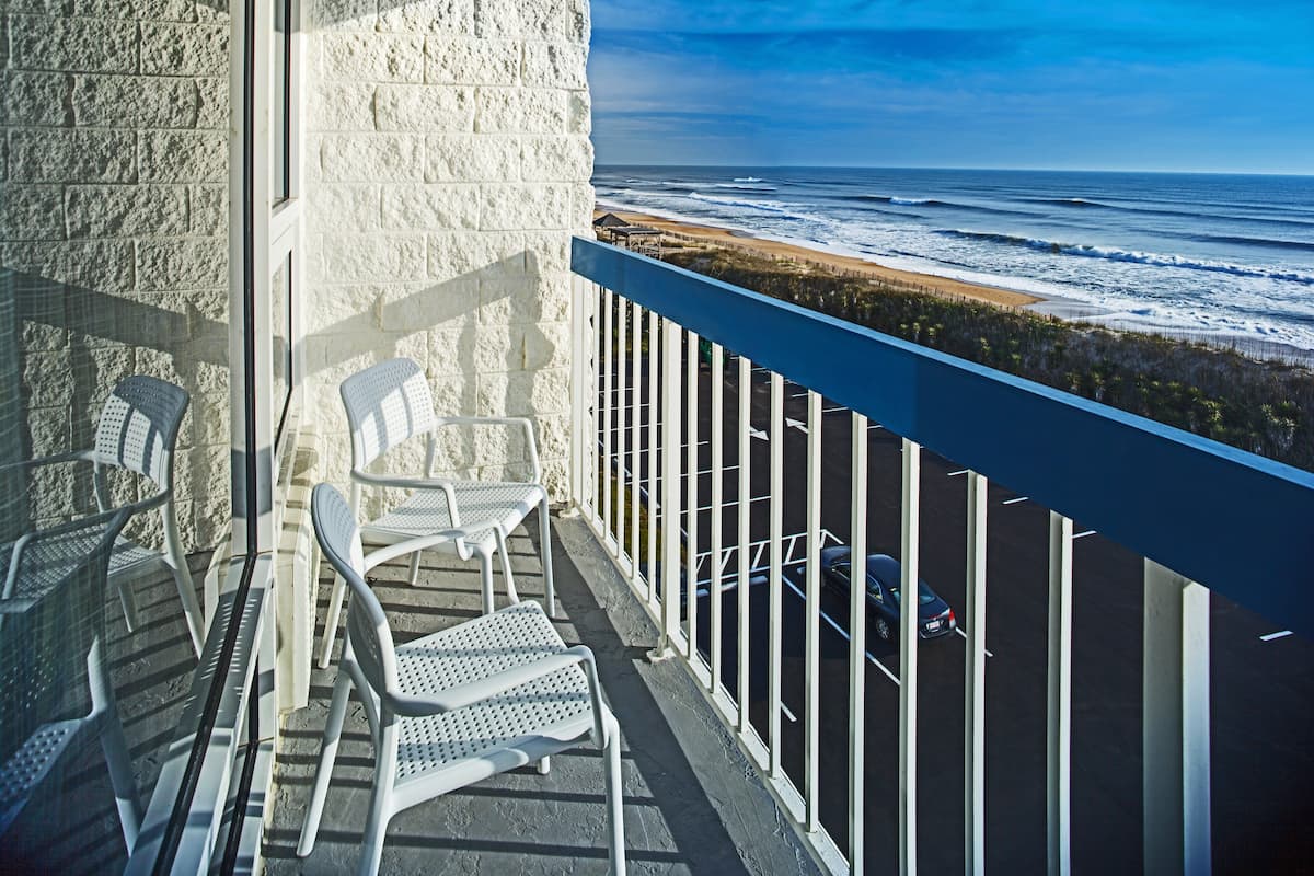 Un balcon avec des chaises blanches et une vue sur l’océan.