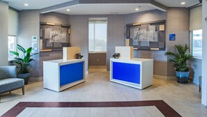 A reception area with two reception desks, a large window, and a plant. - Holiday Inn Express Nags Head Oceanfront by IHG (Nags Head)