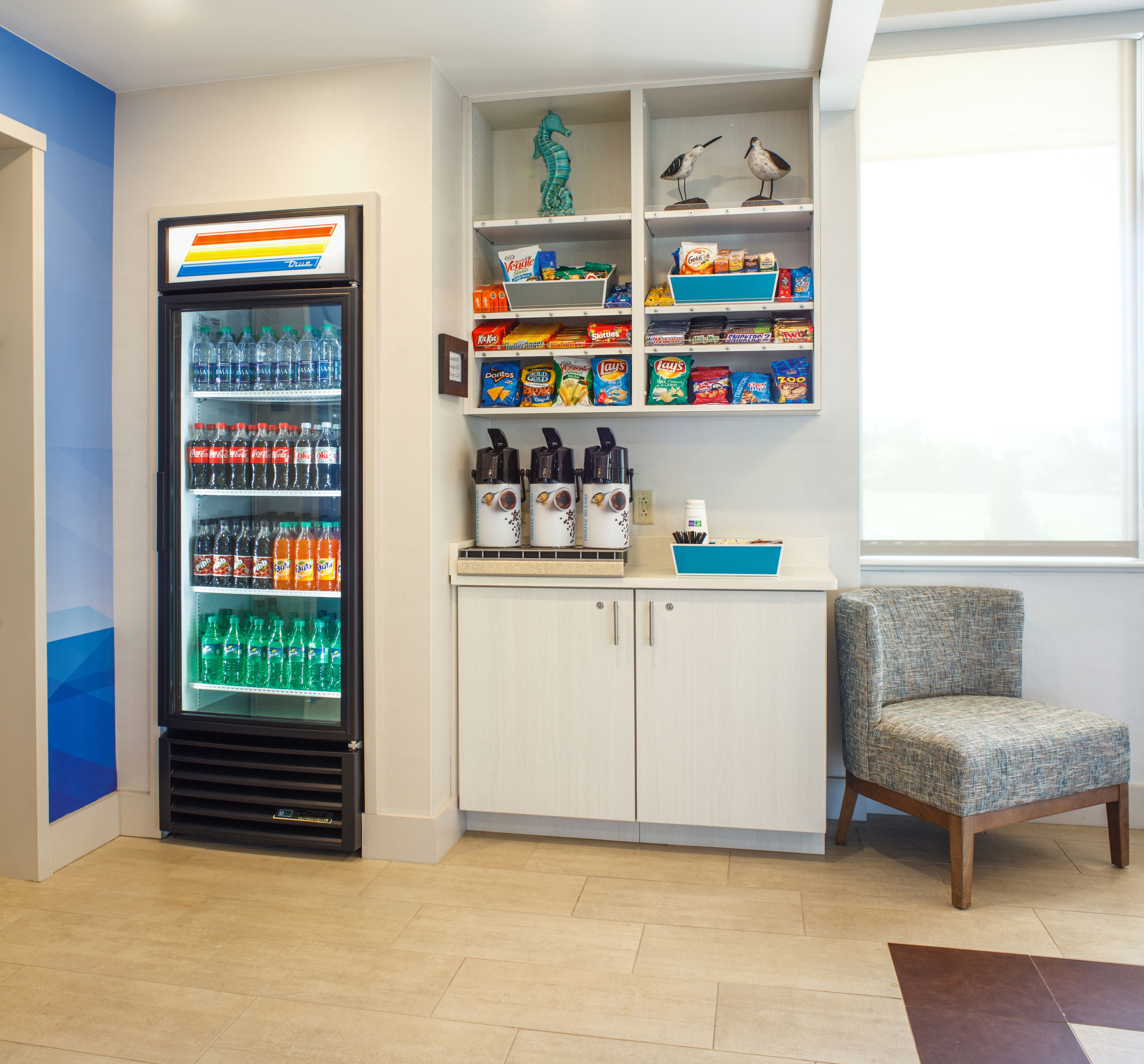 A vending machine with various beverages, a coffee machine, snack shelves, and a seating area.