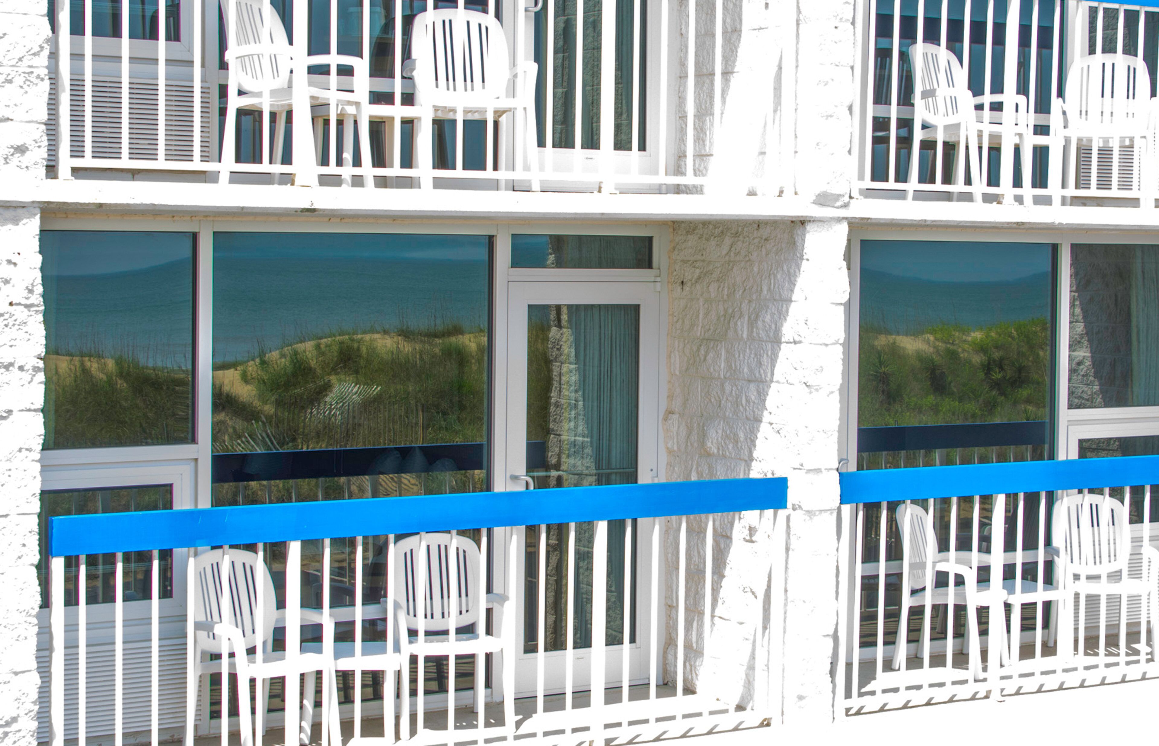 A building with multiple windows, some with views of the sea and greenery.