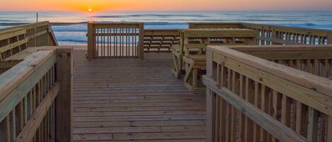 A wooden boardwalk leading to the ocean with railings on both sides.