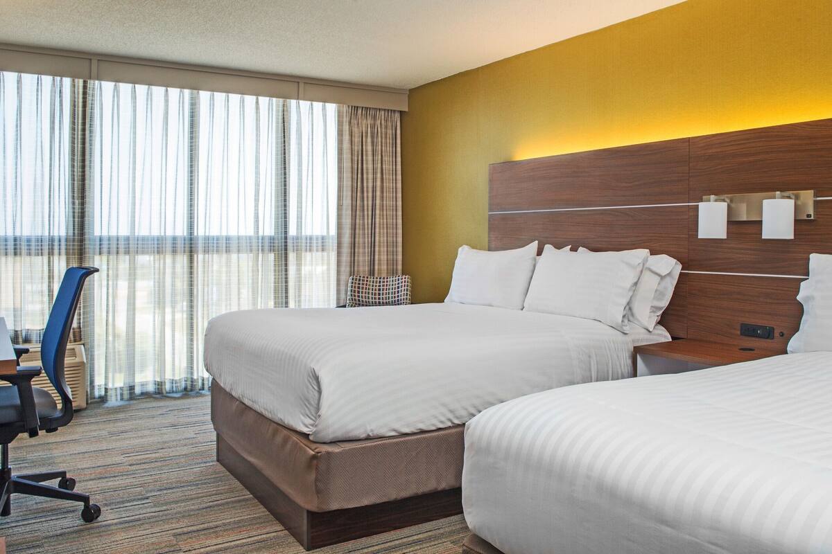 Une chambre d’hôtel avec deux lits, un bureau et une chaise.