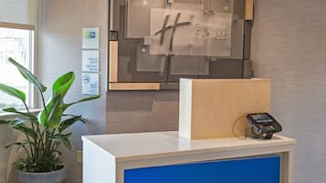 Mostrador de recepción con un panel azul, una planta y un letrero de Holiday Inn Express.