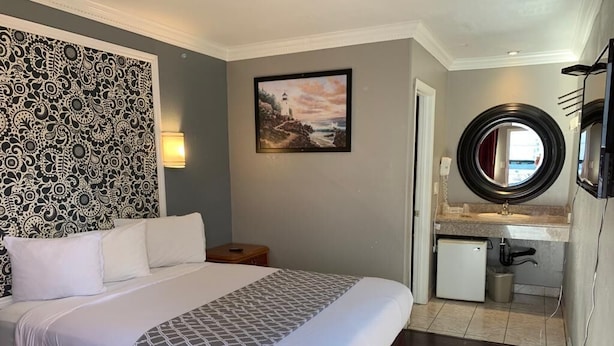 Una habitación de hotel con una cama grande, un escritorio pequeño, un espejo redondo y un cuadro en la pared.