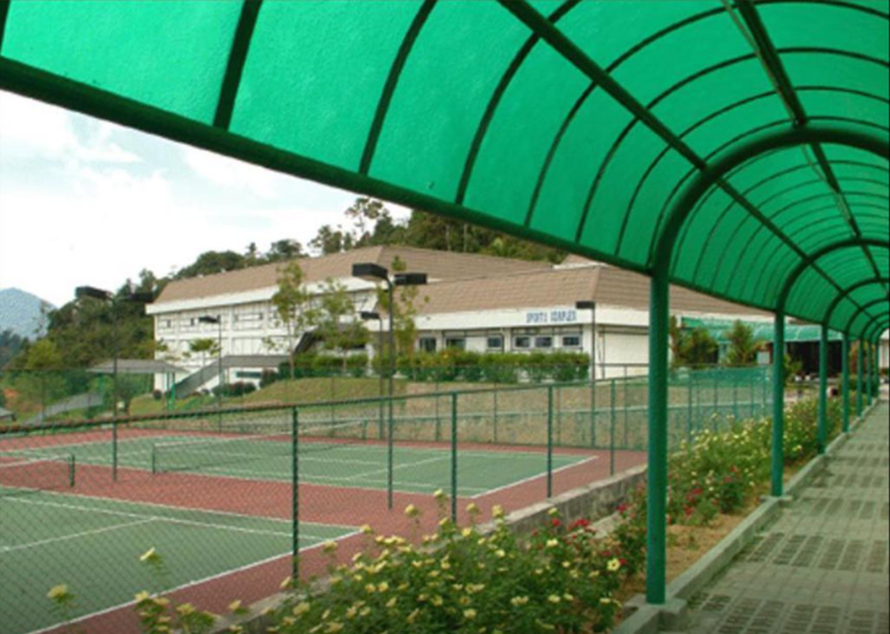 Una cancha de tenis techada con un edificio al fondo.
