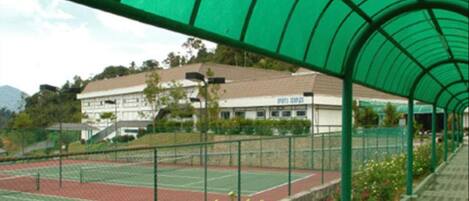 Una cancha de tenis techada con un edificio al fondo.
