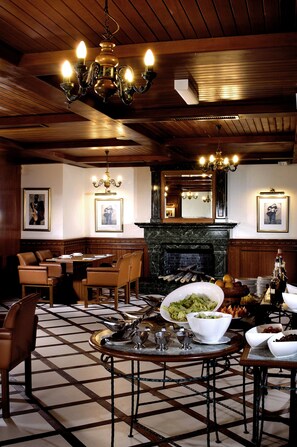 A dining area with a fireplace, wooden paneling, and a chandelier.