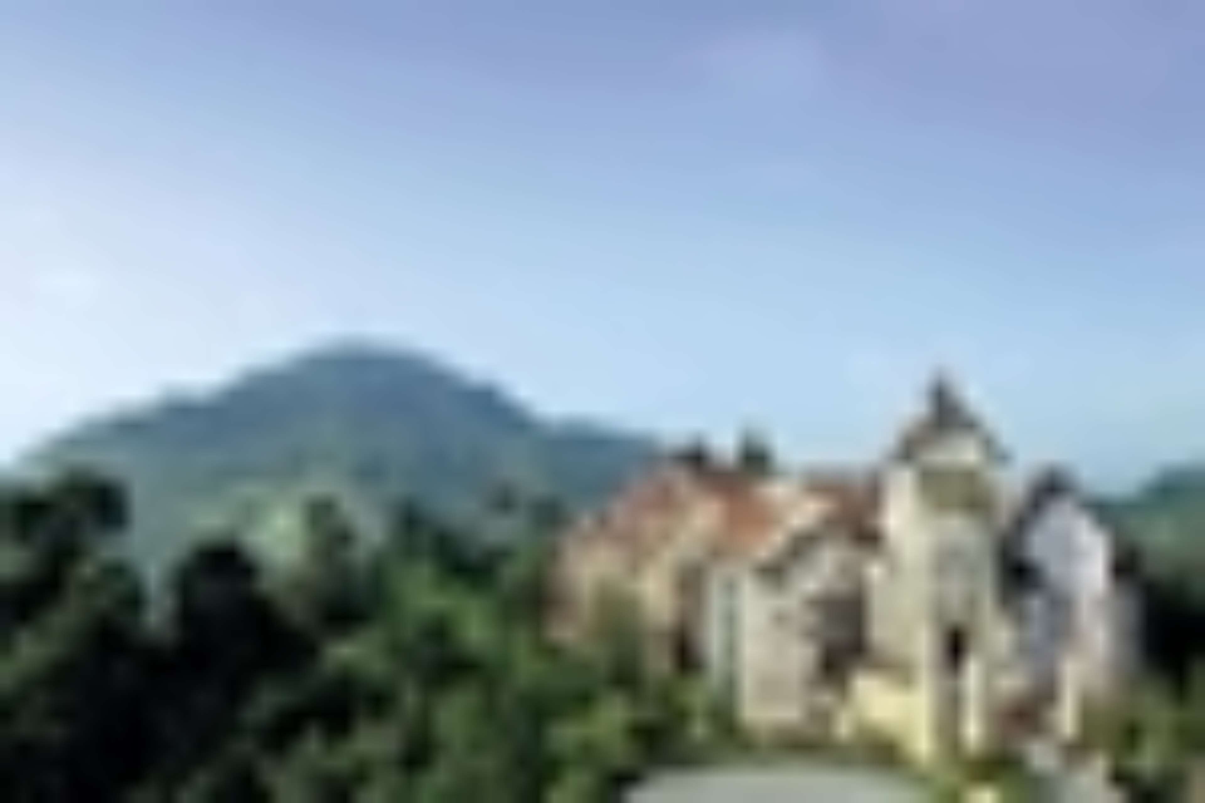A building with a traditional architectural style, surrounded by greenery and mountains in the background.