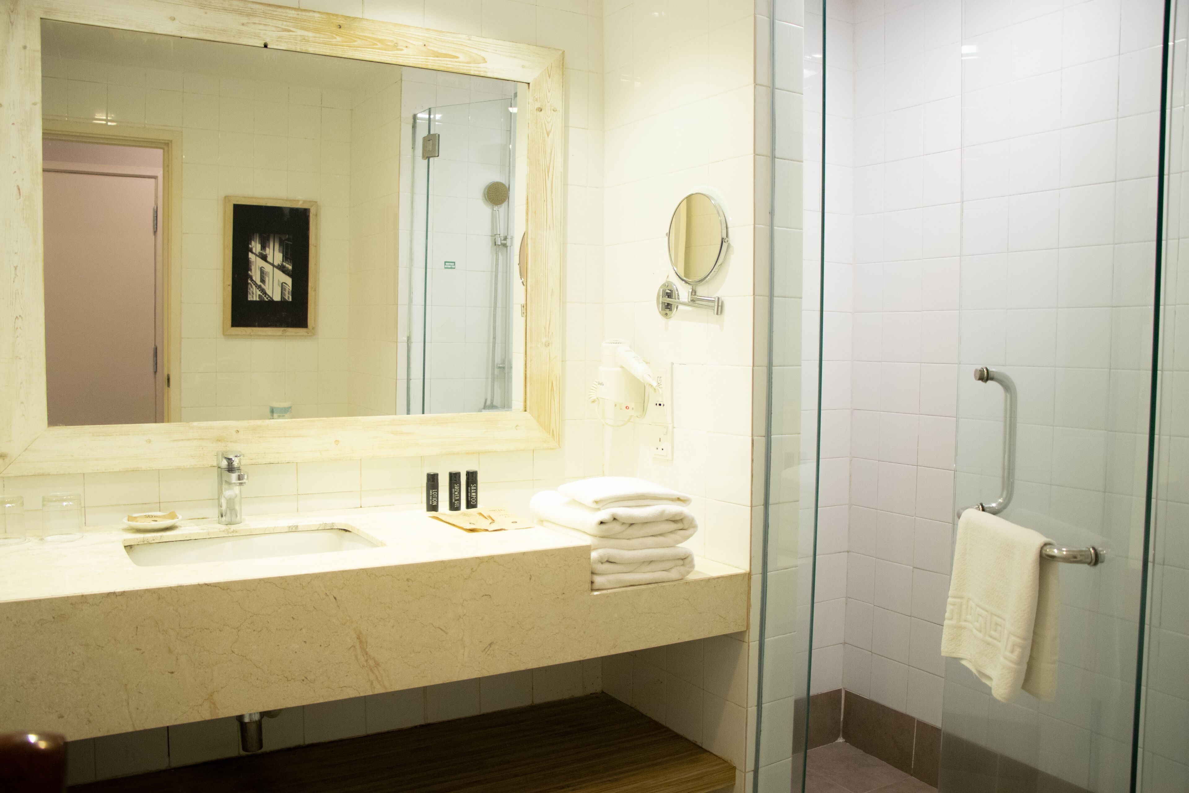 A bathroom with a sink, mirror, and glass shower enclosure.