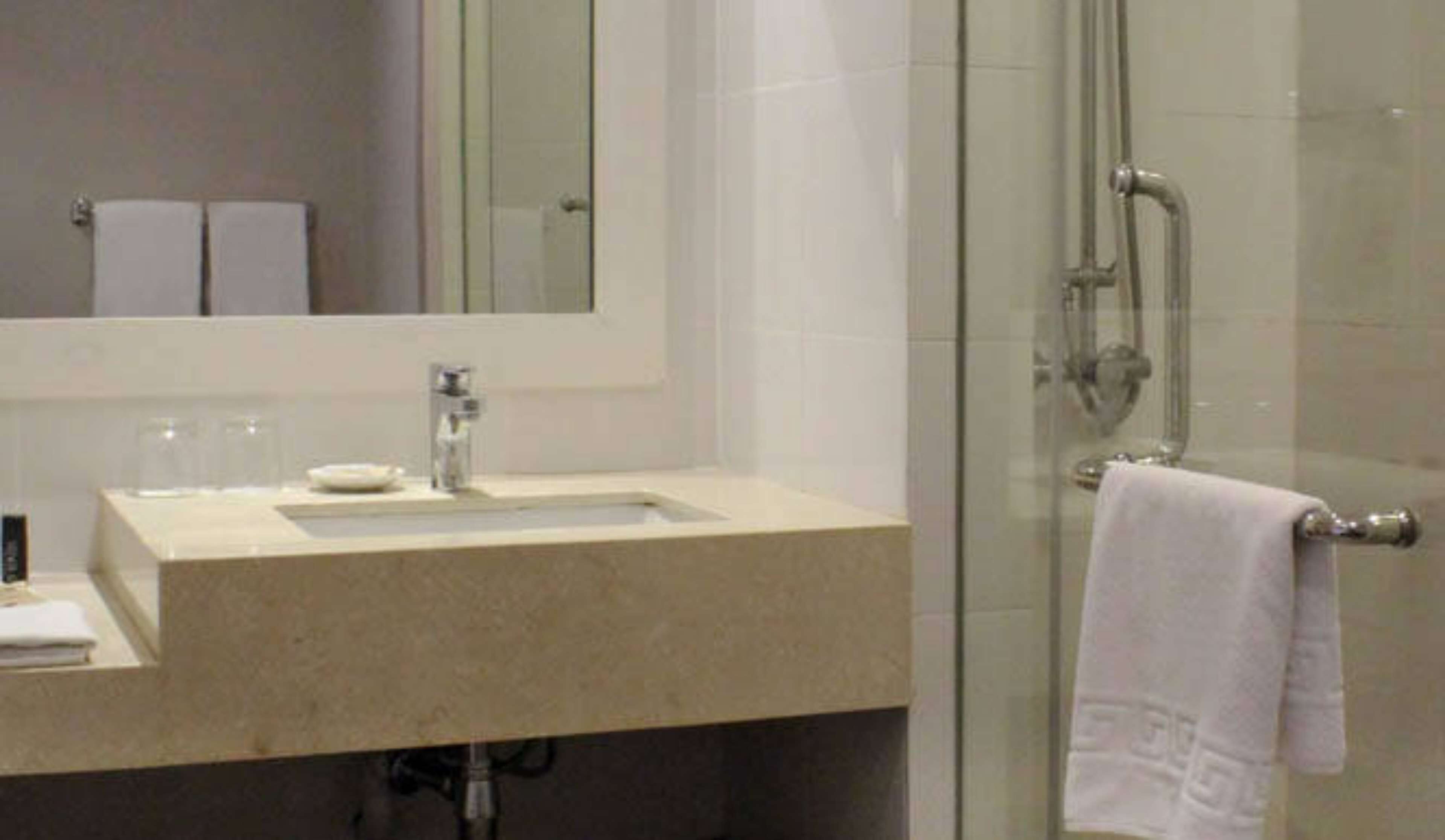 Une salle de bain avec une douche à parois de verre, un lavabo avec un miroir au-dessus et une serviette suspendue à un porte-serviettes.