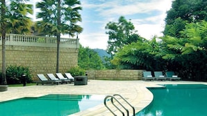 A swimming pool with lounge chairs and a stone wall. - Colmar Tropicale (Bukit Tinggi)
