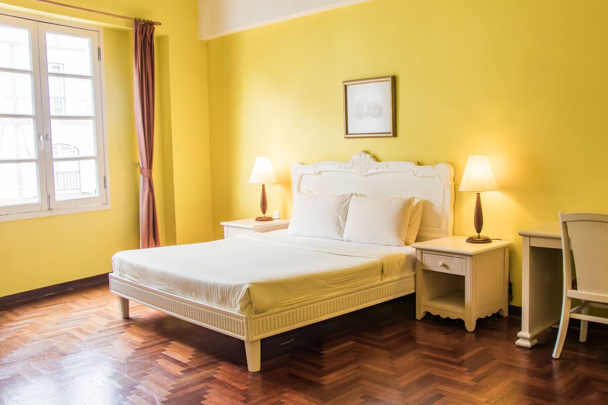 A bedroom with a bed, two bedside tables with lamps, a chair, and a cabinet.