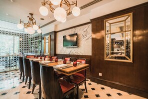 Un comedor con pared de mármol, televisor y espejo estampado.