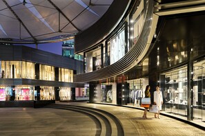 A modern shopping mall with curved architecture and illuminated storefronts.