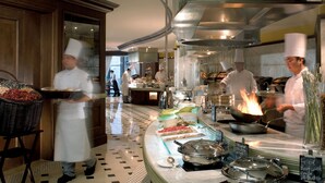 A well-lit, spacious kitchen with chefs preparing food, a buffet line with various dishes, and a modern, elegant interior design. - The Ritz-Carlton, Beijing (Beijing)