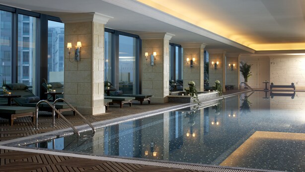 A hotel lobby with a large indoor pool, seating areas, and large windows offering city views. - The Ritz-Carlton, Beijing (Beijing)