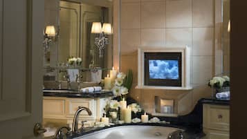 Ein luxuriöses Badezimmer mit einem großzügigen мраморной раковиной, mehreren Spiegeln und einem an der Wand montierten Fernseher.