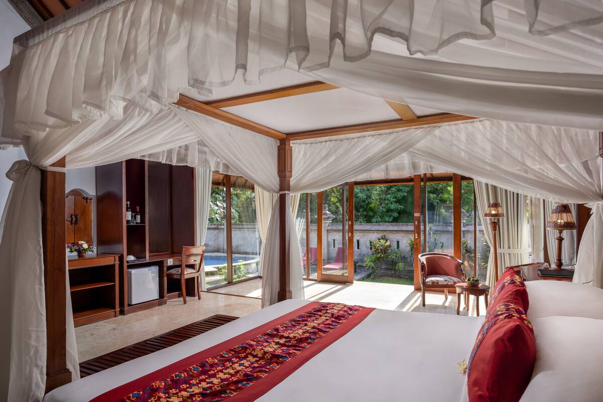 Ein geräumiges Schlafzimmer mit einem großen Bett, einem Schreibtisch und einem Sessel, mit Baldachin und Blick ins Freie.