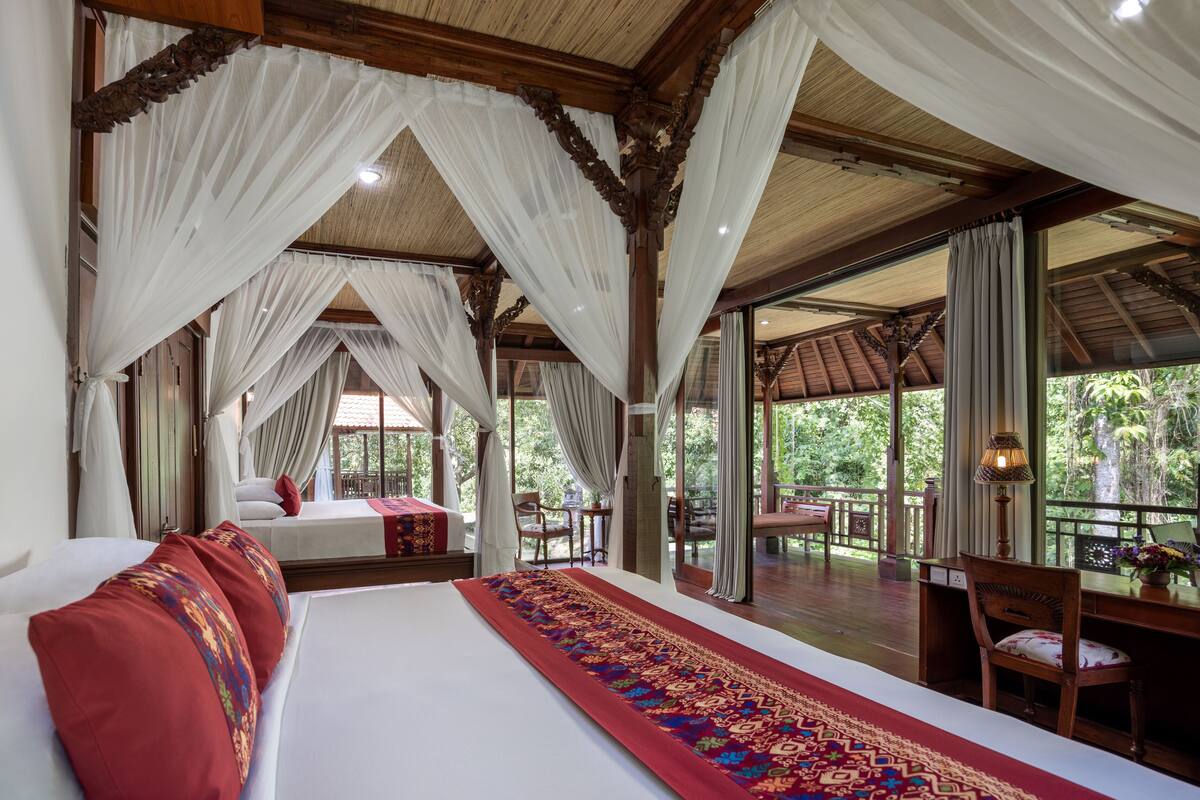 Ein geräumiges Schlafzimmer mit einem großen Bett, einem roten und blauen Teppichläufer und Blick ins Freie.