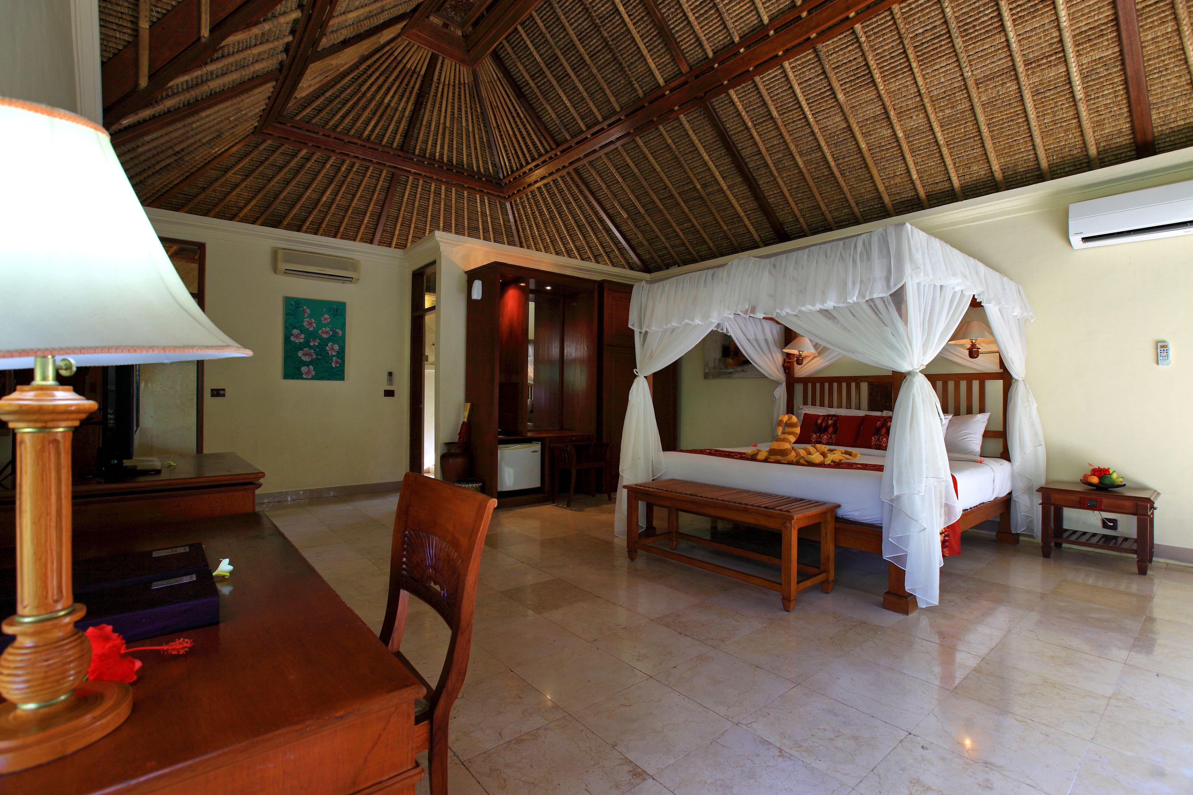 A bedroom with a four-poster bed, a wooden desk, and a chair.