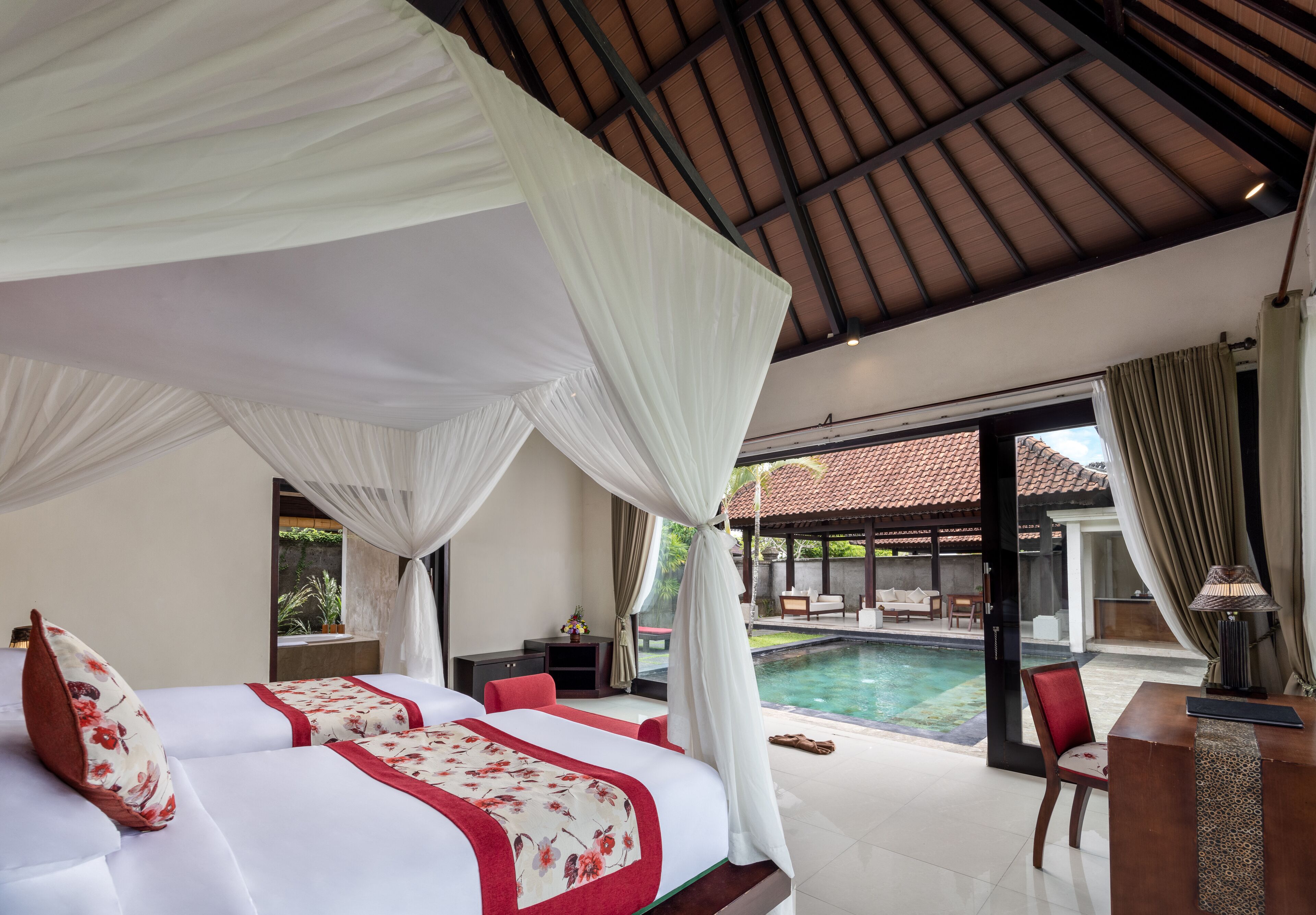 A bedroom with a large bed, a desk, and a view of a swimming pool.
