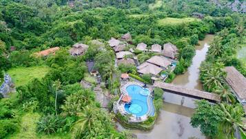 Surrounded by lush greenery and a river, this resort offers a tranquil escape with a central swimming pool.